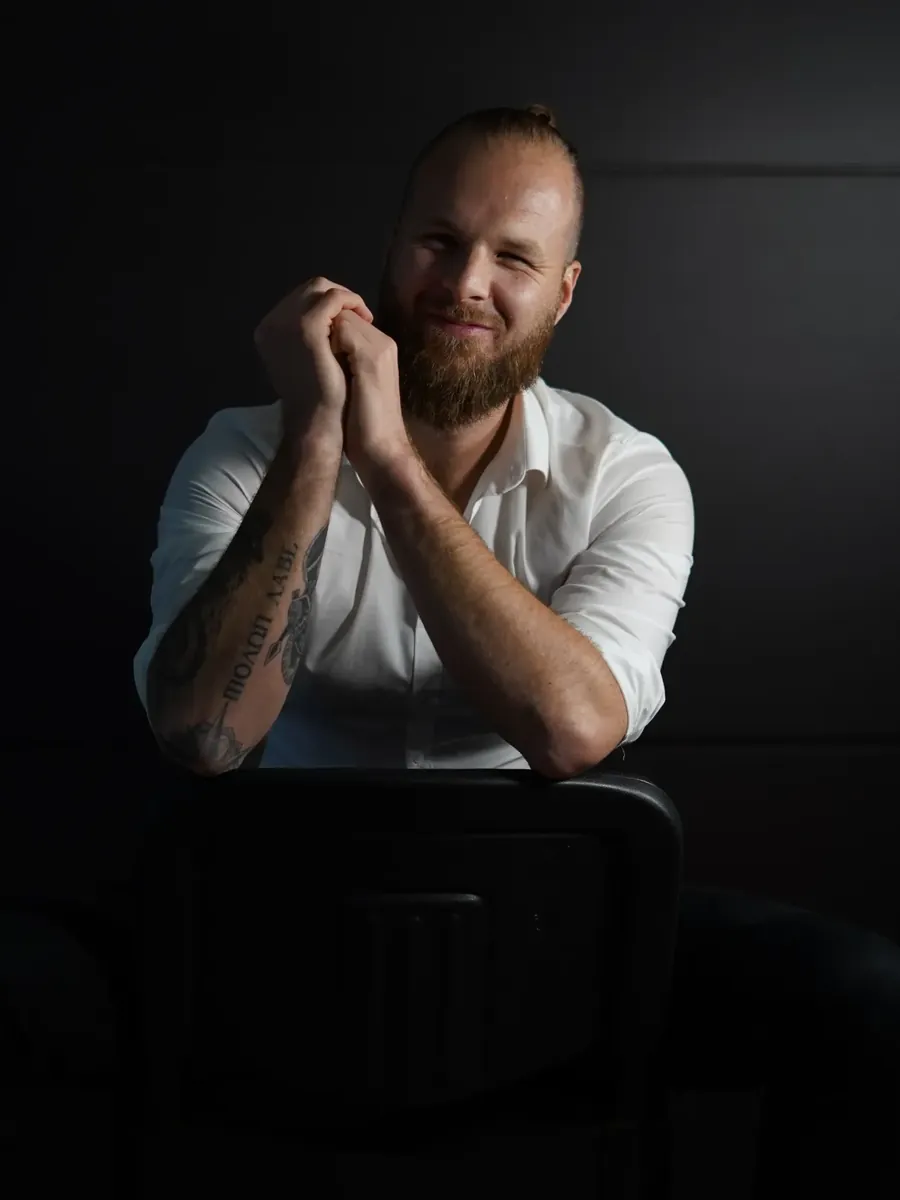 Wouter van de Velde sitting on a chair in a dark studio